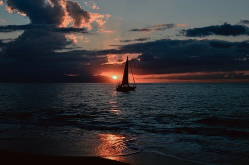 日落期间帆船在水体上的剪影 · 免费素材图片