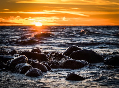 日落海滩上的石头 · 免费素材图片