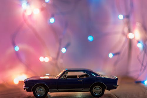 经典蓝色双门跑车压铸模型在桌子上的灯串前面的选择性聚焦摄影 · 免费素材图片