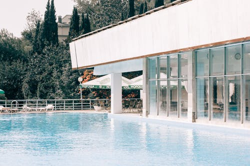 蓝色游泳池附近的白色和灰色混凝土建筑 · 免费素材图片