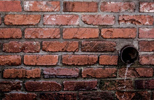 棕色砖墙混凝土中的液体圆形棕色管道排水 · 免费素材图片