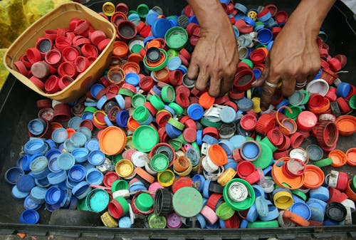 人把手放在各种颜色的塑料盖上 · 免费素材图片