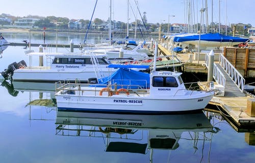 棕色木制海码头附近的白色巡逻救生船 · 免费素材图片