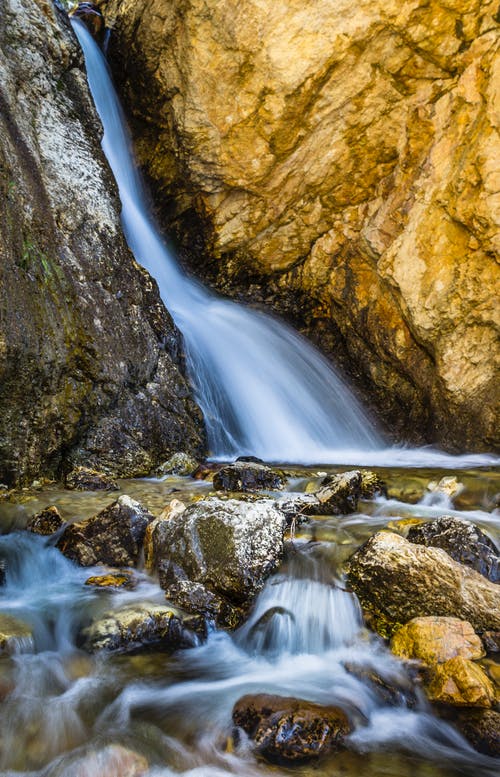 棕色岩石之间的水流 · 免费素材图片