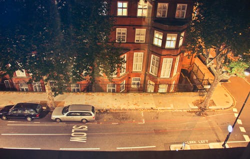 夜间，两辆车停在布朗混凝土大楼附近 · 免费素材图片
