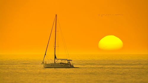 白船在日落海中 · 免费素材图片