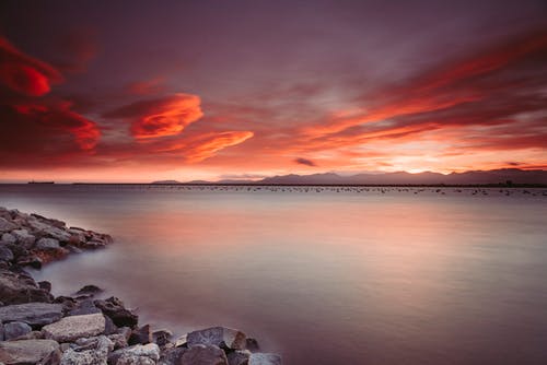 日落期间在水体附近的岩石景观摄影 · 免费素材图片