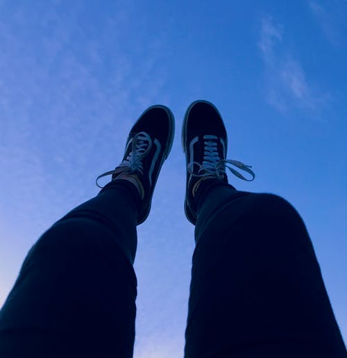 穿货车的人旧的skool运动鞋举起脚指向天空 · 免费素材图片