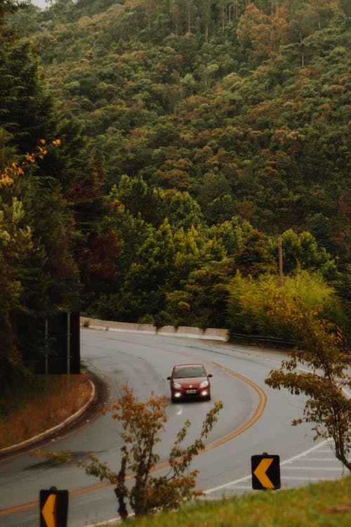 红色汽车在弯曲的道路上行驶 · 免费素材图片