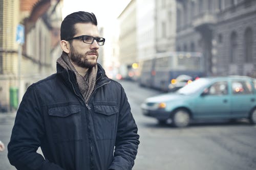 身穿黑色拉链外套站在大街上的男人 · 免费素材图片