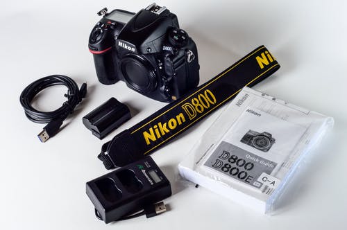 带有挂绳和电池充电器的尼康d800 · 免费素材图片