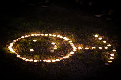 箭头形点燃的茶蜡蜡烛在草地上 · 免费素材图片