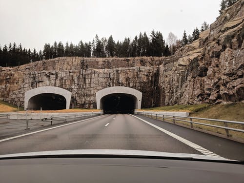 多云的天空下的悬崖上的两个公路隧道的照片 · 免费素材图片