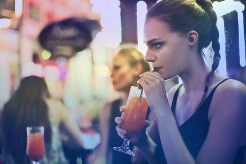 女人穿着黑色意大利面条皮带顶部和and饮饮料 · 免费素材图片
