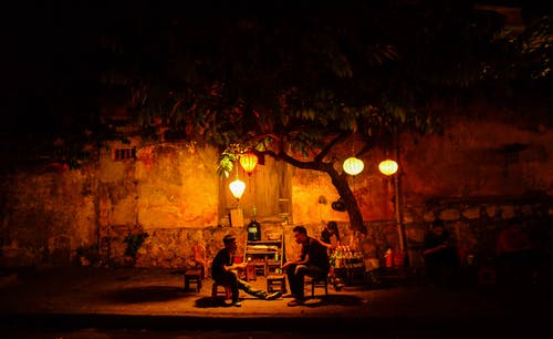 两人在夜间坐在绿树下 · 免费素材图片