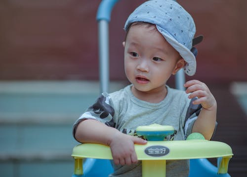 男孩坐在黄色和蓝色的三轮车 · 免费素材图片