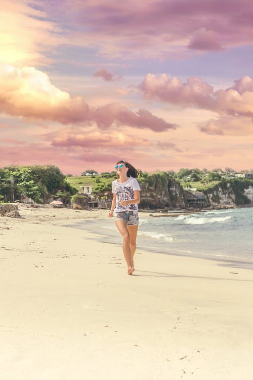 微笑的女人在房屋附近的海边上行走barefood · 免费素材图片