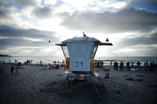 在白色和蓝色的天空下海附近的人 · 免费素材图片