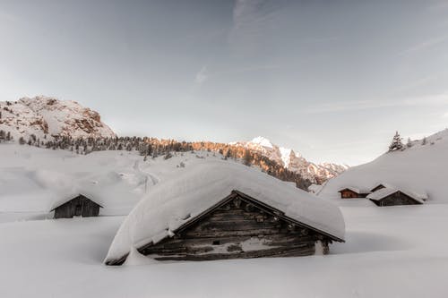 白天白雪覆盖的棕色木制房屋 · 免费素材图片