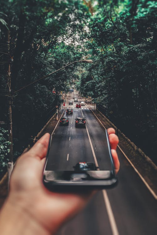 智能手机下方道路上行驶的汽车的强制透视摄影 · 免费素材图片