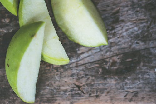 切成薄片的绿色水果，棕色木制表面上的特写摄影 · 免费素材图片
