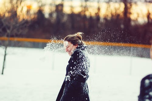 黑色外套的女人打在头上的雪球 · 免费素材图片