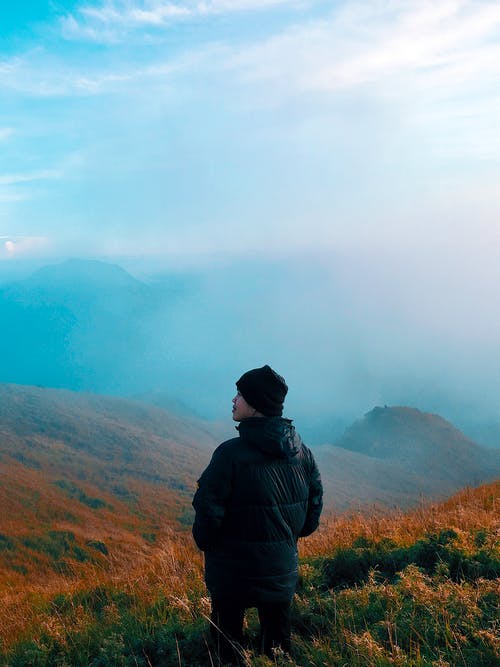 穿黑夹克的男人站在雾山 · 免费素材图片
