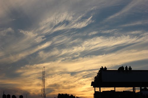 与人们站在黄金时段的建筑轮廓 · 免费素材图片