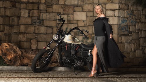 站在巡洋舰摩托车旁边的黑色和灰色长袖连衣裙的女人 · 免费素材图片