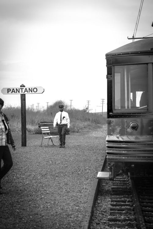 在火车附近行走的人的灰度照片 · 免费素材图片