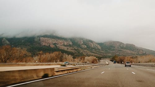 白天在靠近山谷和山脉的4车道道路上的汽车 · 免费素材图片