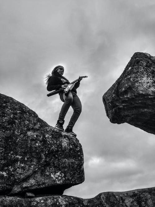 女人在岩层上弹电吉他 · 免费素材图片