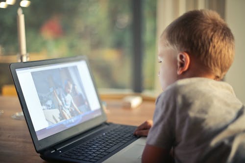男孩看着视频，使用笔记本电脑 · 免费素材图片