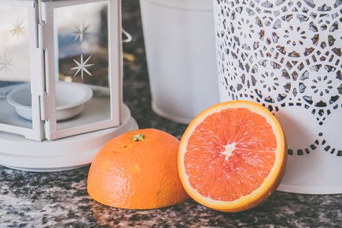 切成薄片的橙色水果附近白色带框玻璃蜡烛灯笼 · 免费素材图片