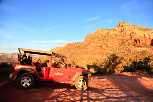 在日落的棕色岩石场上的红色全地形车 · 免费素材图片