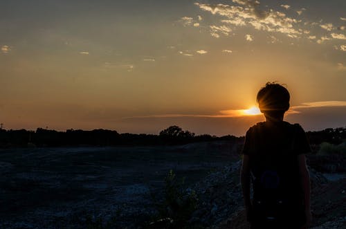 一个男孩在日落的剪影 · 免费素材图片