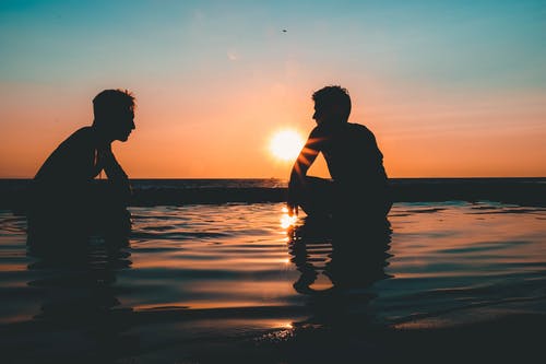 两名男子在日落海滩上的照片 · 免费素材图片