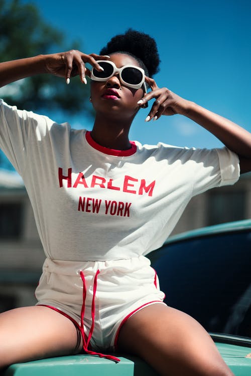 女人穿着白色和红色的哈林纽约印花圆领蝙蝠翼袖衬衫与抽绳海豚短裤 · 免费素材图片
