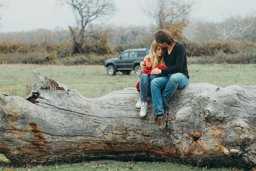 母亲和女儿坐在树原木上 · 免费素材图片