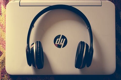 白色hp笔记本电脑附近的黑色无线耳机 · 免费素材图片