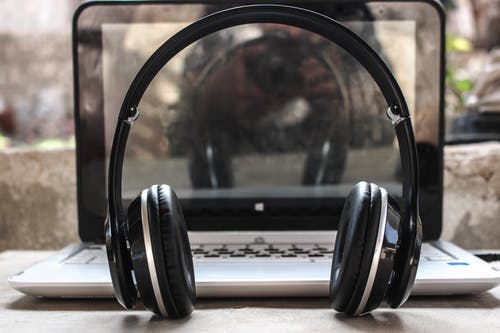 黑色无线耳机在笔记本电脑前的照片 · 免费素材图片