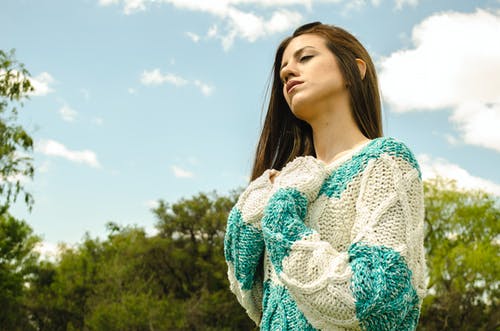 多云的天空下的白色和蓝绿色钩针编织衣服的女人 · 免费素材图片