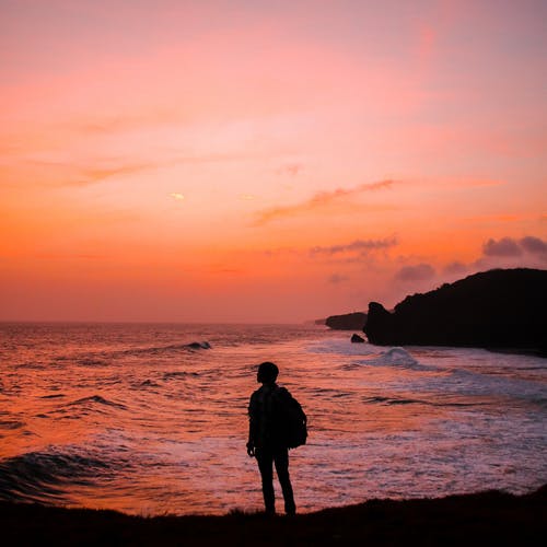 人的剪影照片有背包的在金黄小时站立在海滨 · 免费素材图片