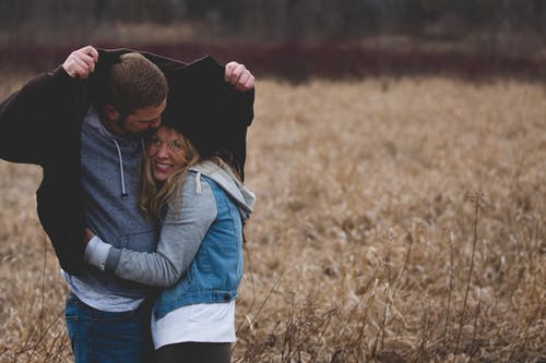 男人和女人在棕地上拥抱 · 免费素材图片