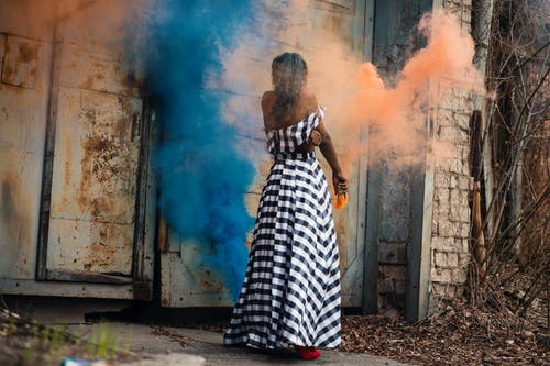 女人站在橙色和蓝色的烟雾 · 免费素材图片