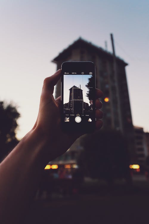 拿着iphone的人拍摄建筑物的照片 · 免费素材图片