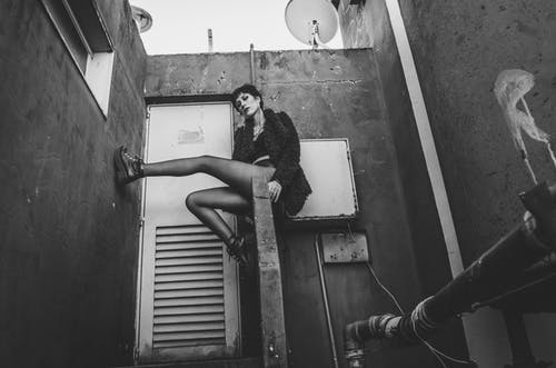 坐在混凝土扶手上的皮大衣的女人 · 免费素材图片