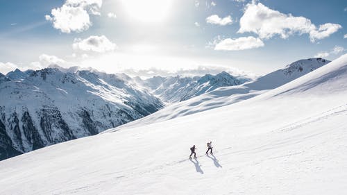 两个男人在雪山上徒步旅行 · 免费素材图片
