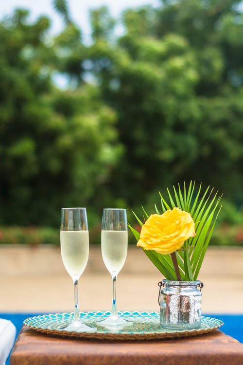 黄玫瑰花朵核心和两个透明的香槟槽 · 免费素材图片