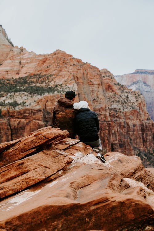 夫妻坐在岩石峭壁上 · 免费素材图片